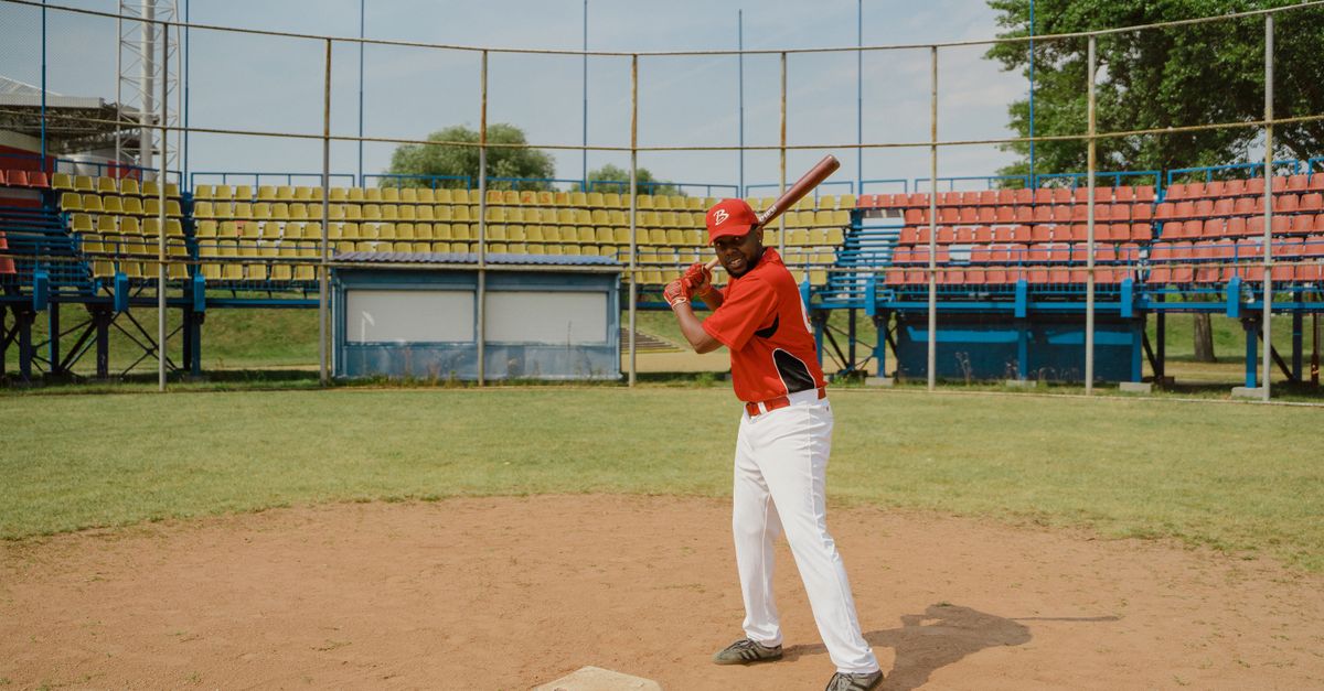 African American baseball player poised to bat at an outdoor field with vibrant seating.