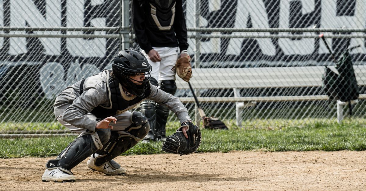 Dynamic capture of a baseball catcher in position during a practice session at an outdoor field.